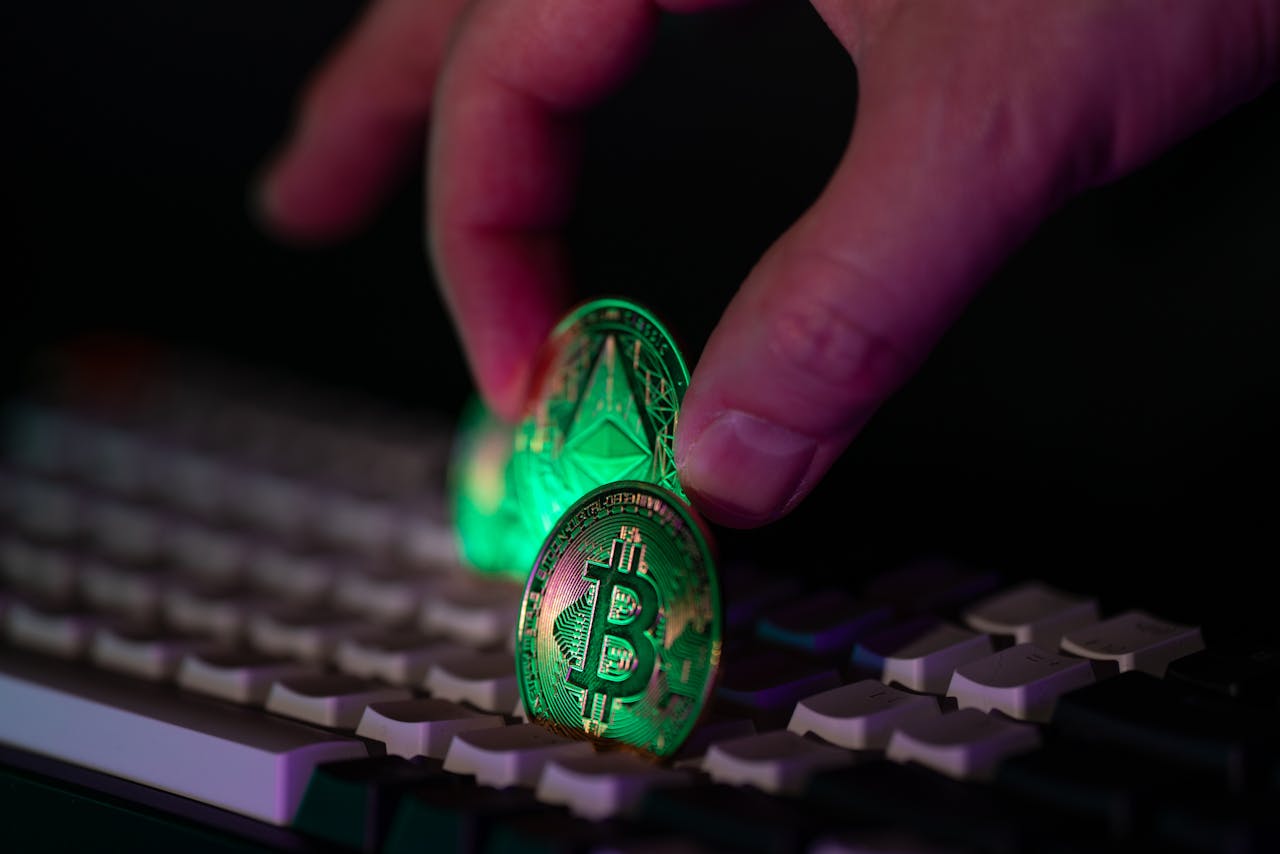 Services-01 Close-up of a hand placing bitcoin and ethereum coins onto a computer keyboard, symbolizing cryptocurrency and digital finance.